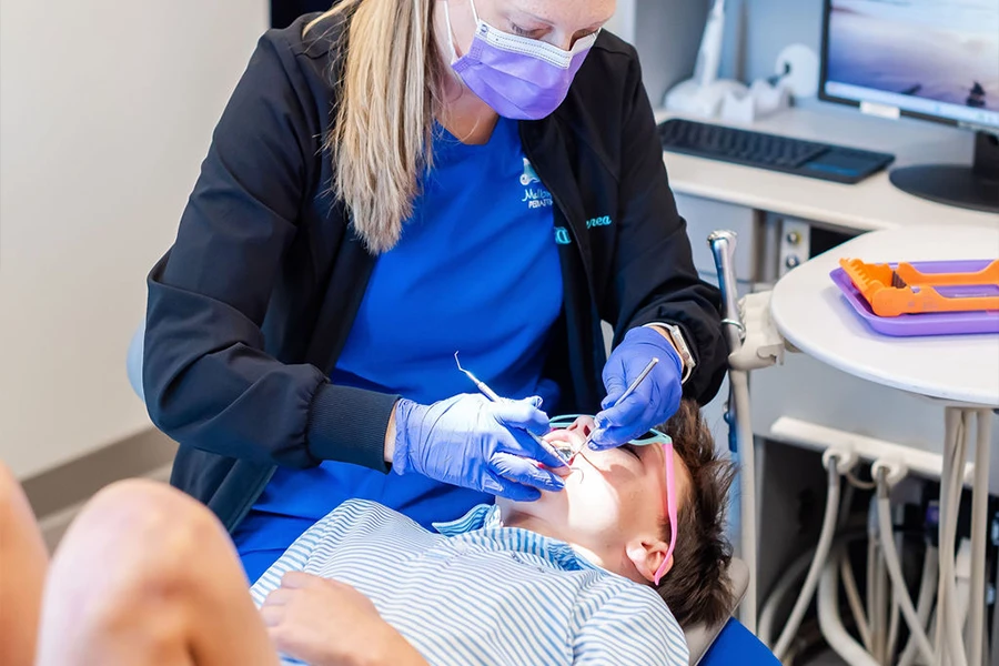 Pediatric dentist performing dental exam on young patient