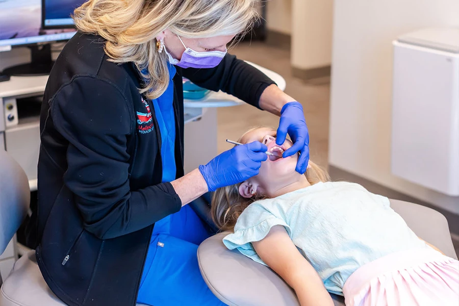 Dentist cleaning a child's teeth while the child wears protective eyewear