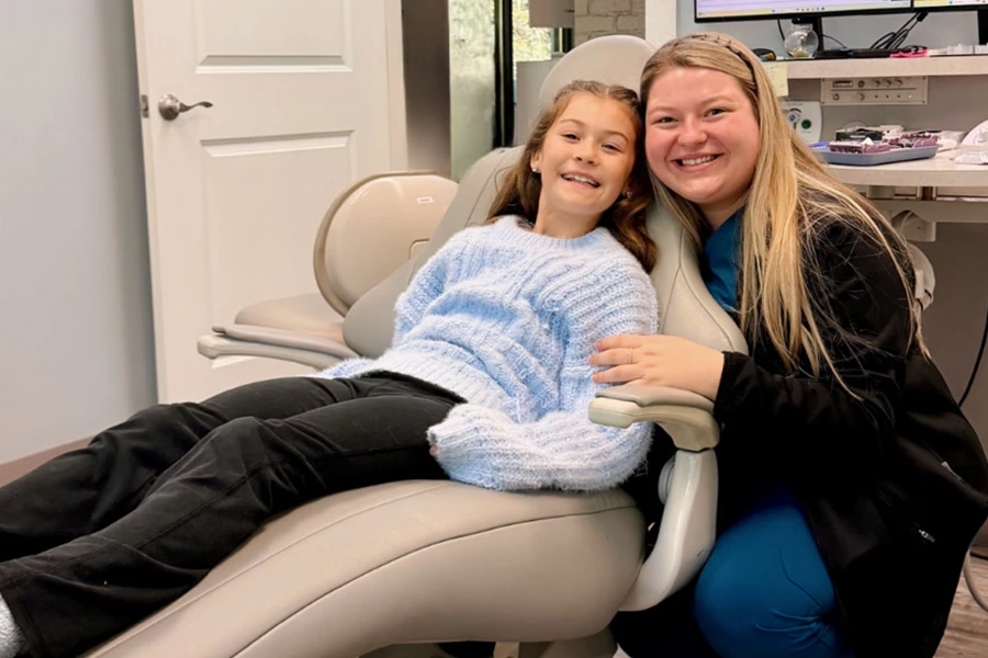 Dental hygienist smiling with young female patient in treatment chair