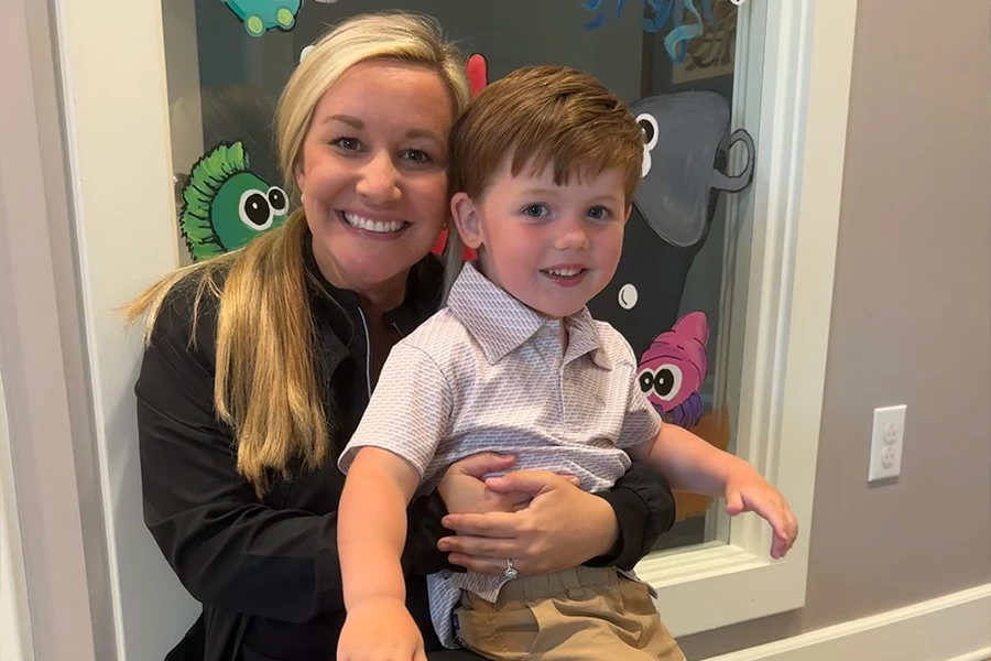 Pediatric dentist holding a young toddler boy in front of a decorated office door