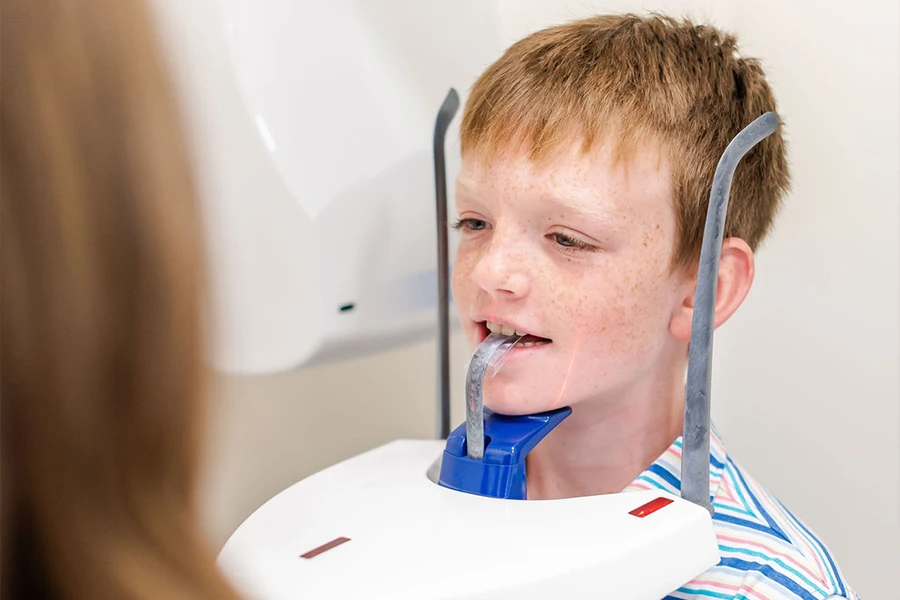 Young boy getting panoramic dental X-ray at pediatric dentist office